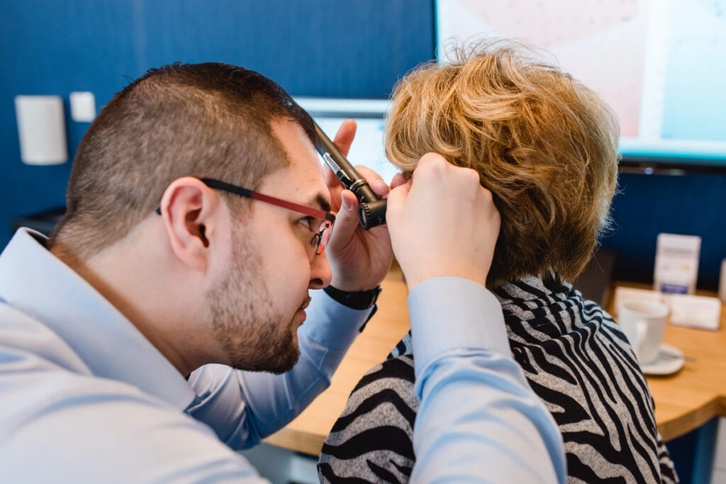 Nahaufnahme einer Ohruntersuchung mit Otoskop durch den Hörakustiker.