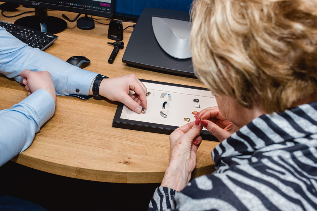 Kundin wählt ein Hörgerät aus einer Auswahl verschiedener Modelle.